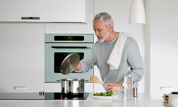 Man vid spis som lagar mat