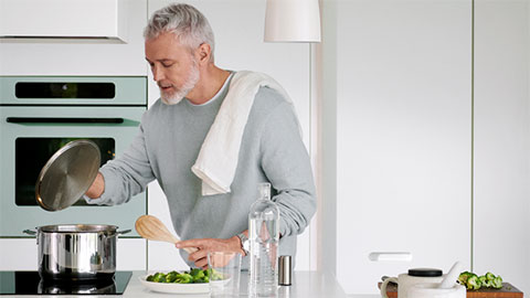 Man som lagar mat vid en spis