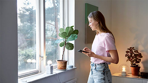 Kvinna med kaffekopp tittar ut genom ett fönster