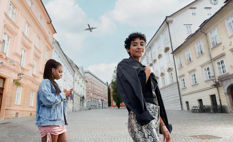 Två kvinnor som står på en kullerstensgata mellan två hus