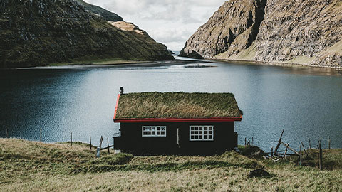 Ett hus framför en sjö med berg i bakgrunden