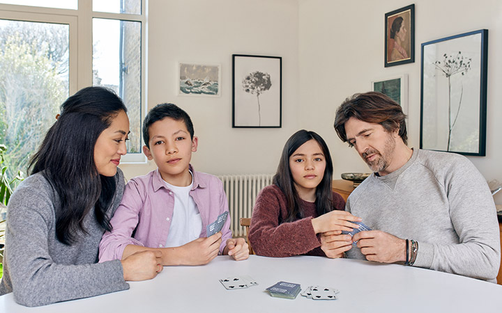 Familj med föräldrar och två barn som spelar kort tillsammans