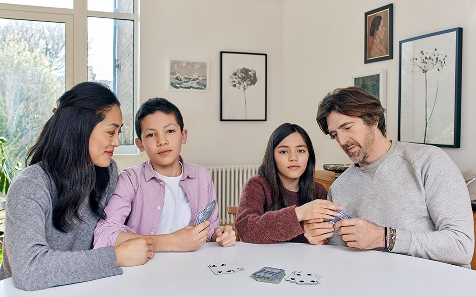 Familj med föräldrar och två barn spelar kort tillsammans