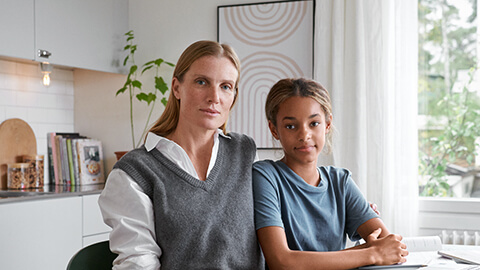 En kvinna och flicka sitter vid bordet och tittar åt kameran.