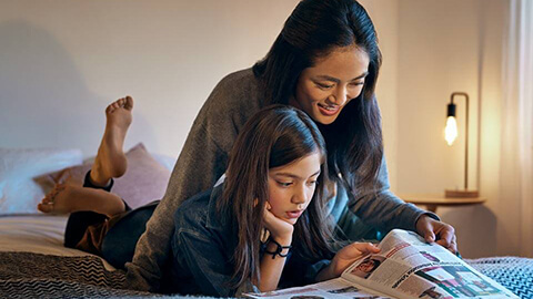 En kvinna och en flicka läser i sängen.