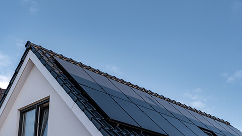 Hustak med solceller, blå himmel i bakgrunden.