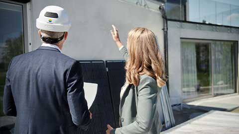Man och kvinna inspekterar hus med solceller