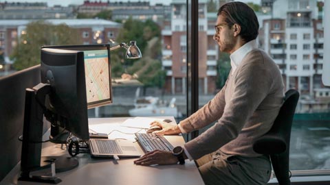 Man som sitter framför en dator i ett kontorslandskap