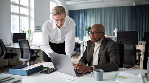 Kllegor som står framför en dator och samtalar