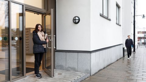 Kvinna påväg ut från en port i ett flerfamiljshus