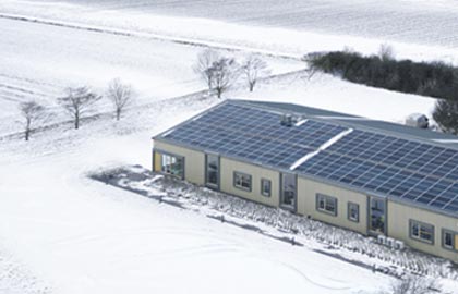 Ett hus med solceller i ett snötäckt vinterlandskap
