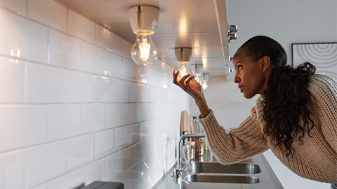Kvinna håller i lampa i köket