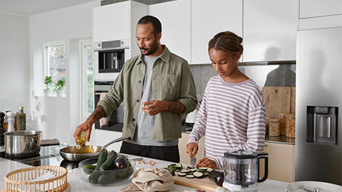 En familj står i ett kök och lagar mat.