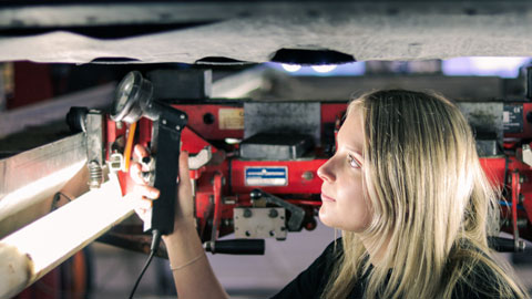 Kvinna som besiktigar underredet av en bil