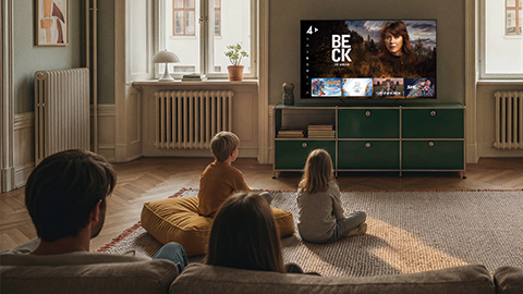 En familj sitter i vardagsrummet och kollar på TV.