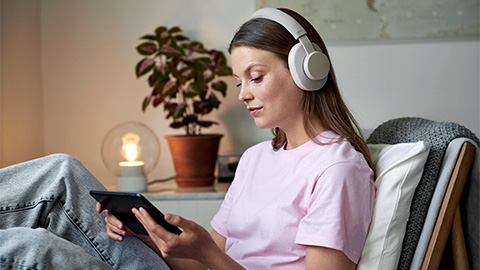 Kvinna sitter i en fåtölj och läser på en surfplatta